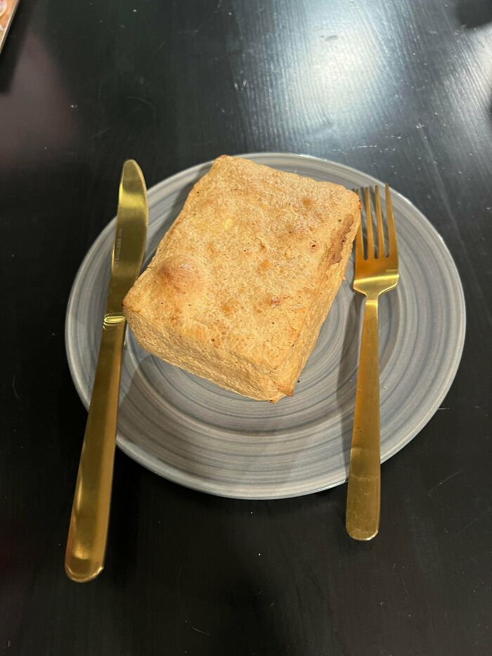 A plain rectangular piece of vegan food on a grey plate with gold cutlery, representing stupid vegan food.