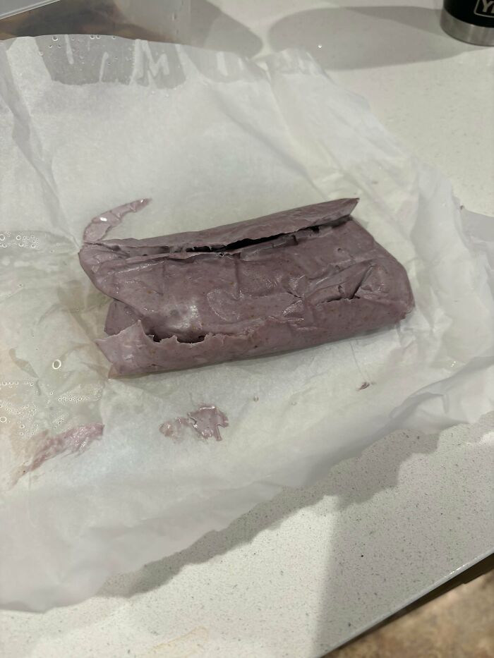 A purple, wrapped food item on white paper, showcasing a piece of stupid vegan food.