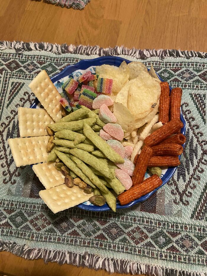 A blue plate filled with various snacks like crackers, chips, and candies, representing stupid vegan food.