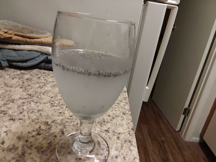 A glass of chia seed water on a speckled countertop, showcasing more stupid vegan food.
