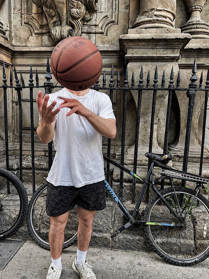 A photographer captures perfectly timed coincidences: a person with a basketball perfectly obscuring their face, standing in Barcelona.