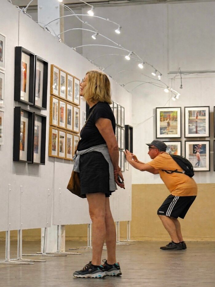 A photographer captures perfectly timed coincidences: a man subtly holding a woman's arm in a Barcelona art gallery.