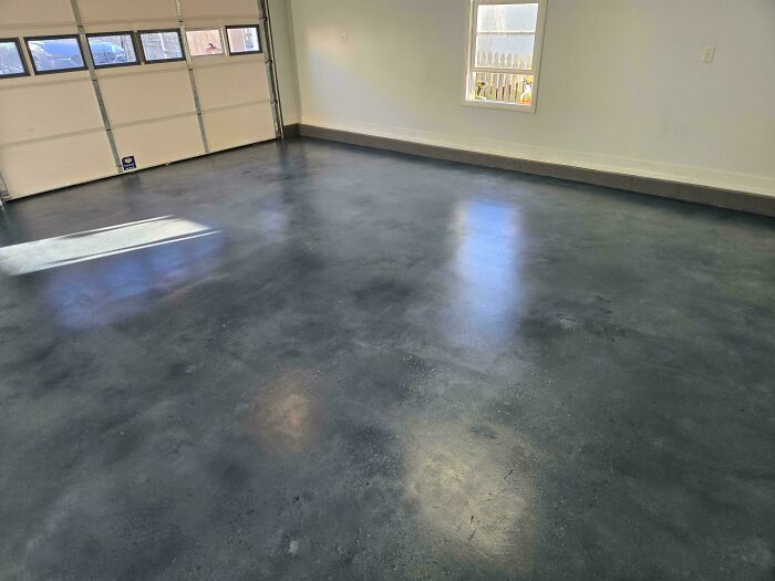 A spacious garage with a newly finished, sleek dark gray floor, a testament to impressive home DIY projects.