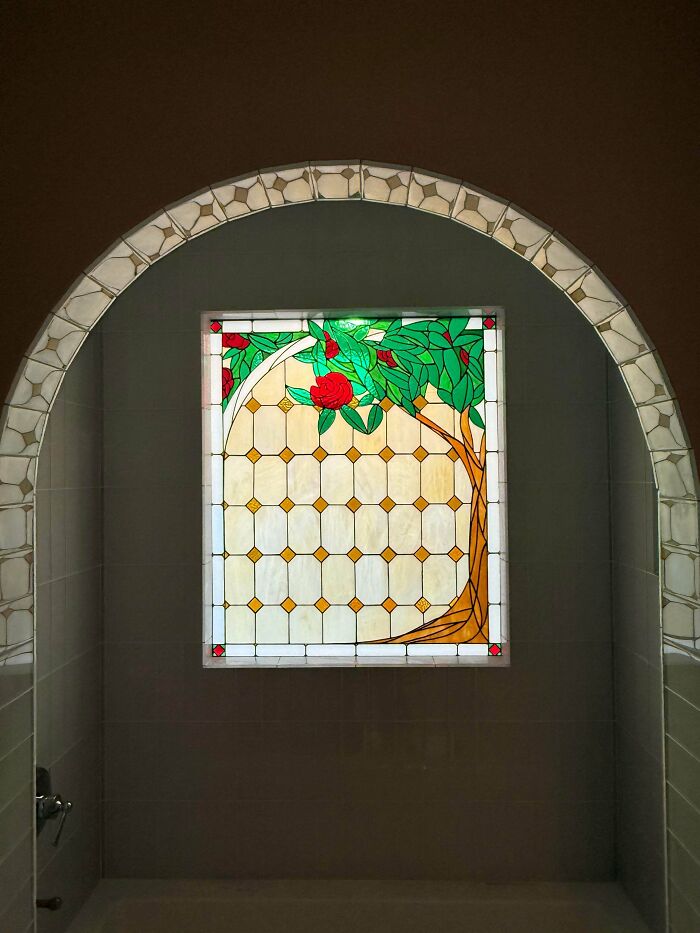 A stunning home DIY project featuring a beautiful stained glass window with a tree and red rose design in an arched alcove.