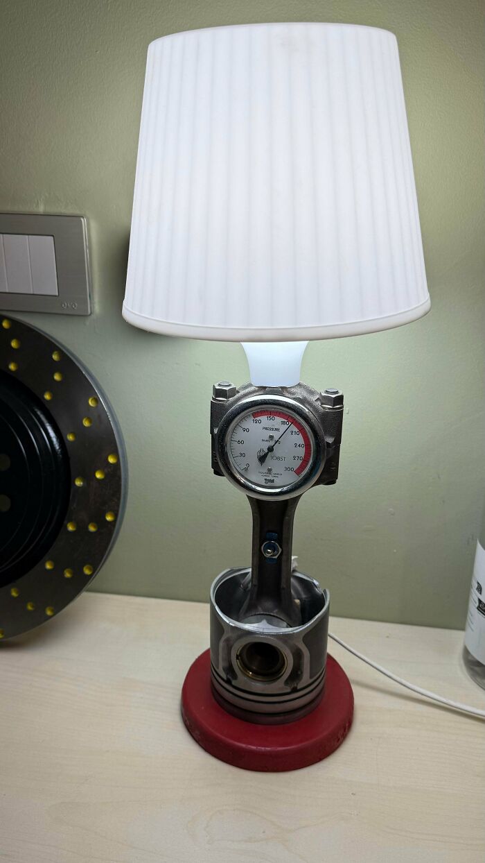 Creative Home DIY Projects: An industrial-style table lamp made from a car piston and pressure gauge, with a white shade.