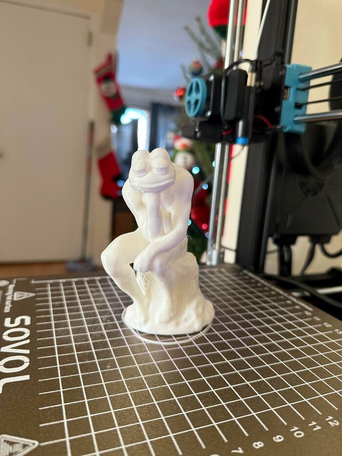 A thoughtful frog figurine, similar to Rodin's The Thinker, created with a 3D printer, showcasing cool and useful 3D prints.