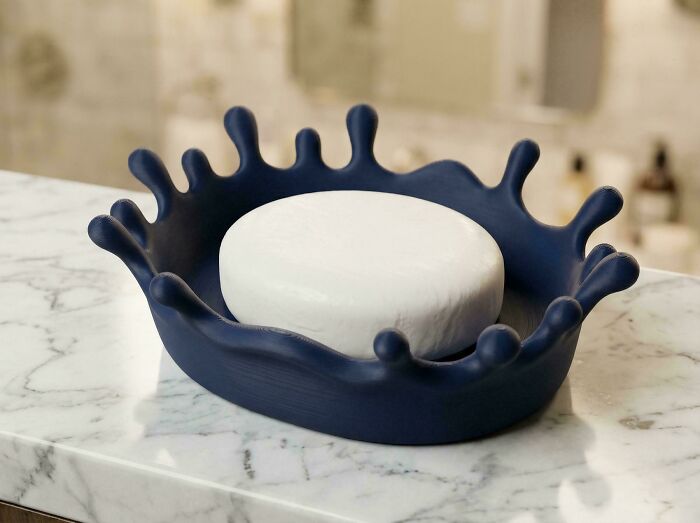 Blue splash-shaped soap dish holding a white bar of soap, a cool thing people printed with 3D printers.