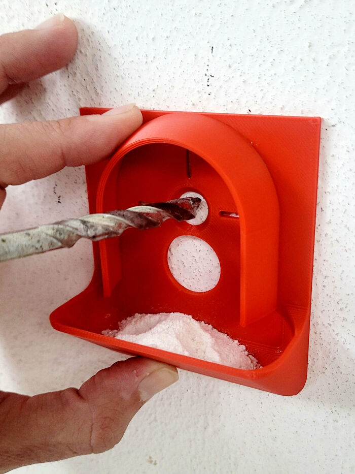 A person holding a drill and an orange dust collector, a cool and useful thing printed with 3D printers.