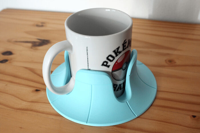 A white Pokémon mug in a light blue 3D printed coaster, a useful thing.