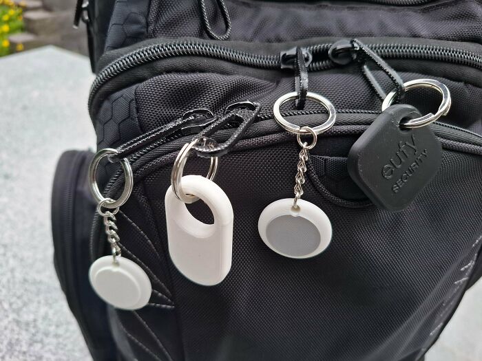Various 3D printed tags and trackers attached to a black backpack, showcasing useful prints.