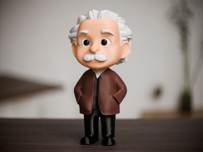 A charming 3D printed bobblehead-style figure of Albert Einstein with white hair and a brown jacket.