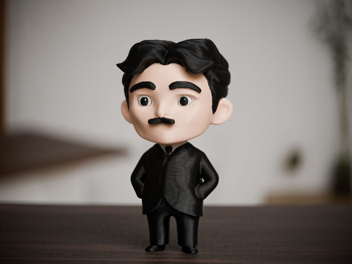 A cute 3D printed bobblehead-style figure of a man with a mustache in a black suit.