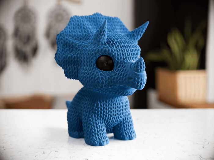 A blue textured dinosaur figurine, a cool thing people printed with their 3D printers.