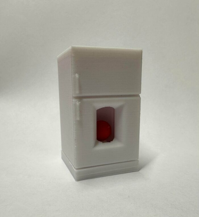 A miniature 3D printed refrigerator with a red object inside, one of the useful things people printed.