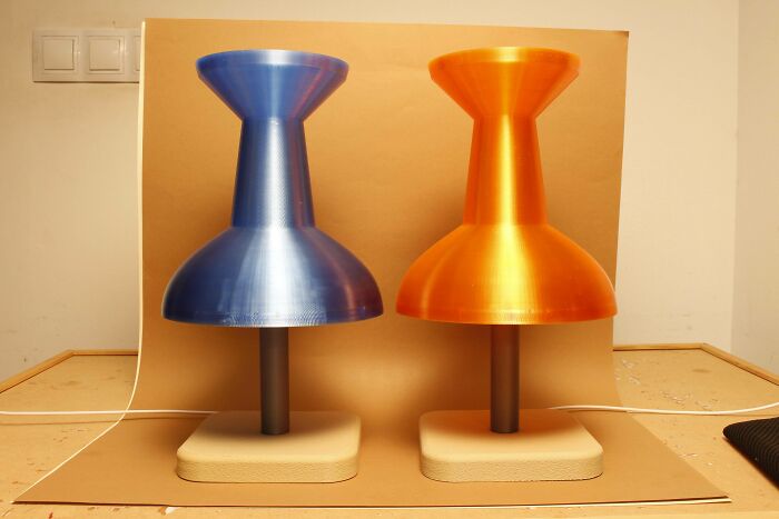 Two large, colorful thumbtack-shaped objects, one blue and one orange, showcasing cool and useful things people printed with their 3D printers.