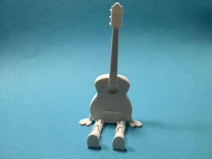 A charming 3D printed guitar figure with articulated legs and arms, a cool and useful print.