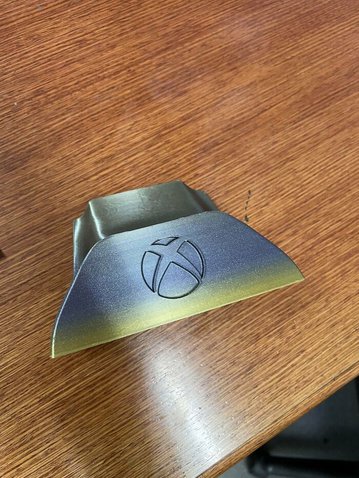 An Xbox controller stand, a cool and useful item printed with 3D printers, on a wooden desk.