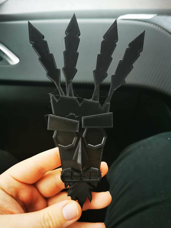 A hand holding a black, stylized mask with feather-like protrusions, among the cool and useful things people printed with their 3D printers.