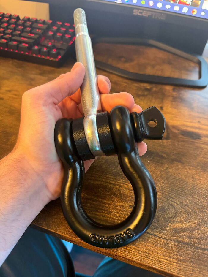 A hand holding a metal shackle, a cool and useful thing people printed with their 3D printers.