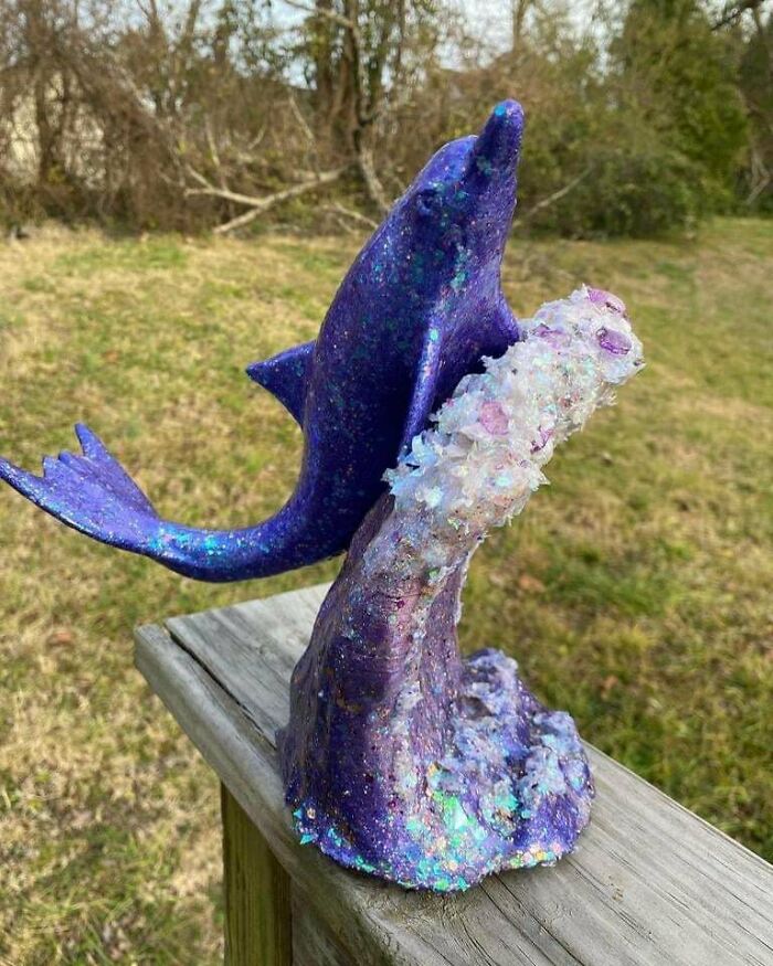 A shimmering purple dolphin sculpture leaping from a glittery wave, a cool and useful thing printed with a 3D printer.