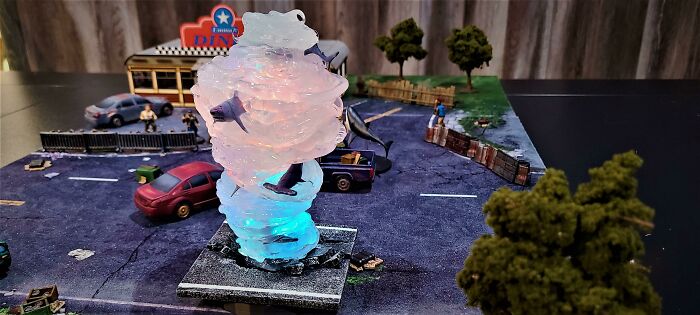 A detailed diorama featuring a transparent, glowing 3D printed sharknado, an example of cool things people printed.