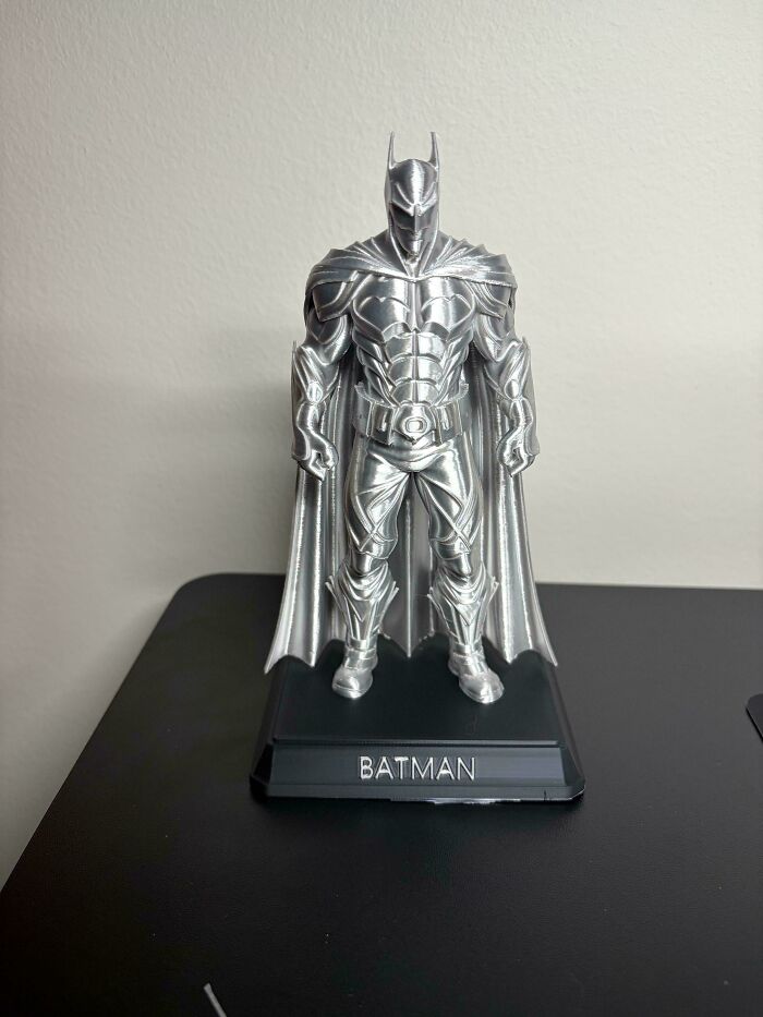 A shiny 3D printed Batman statue on a black base, a cool thing people printed with their 3D printers.