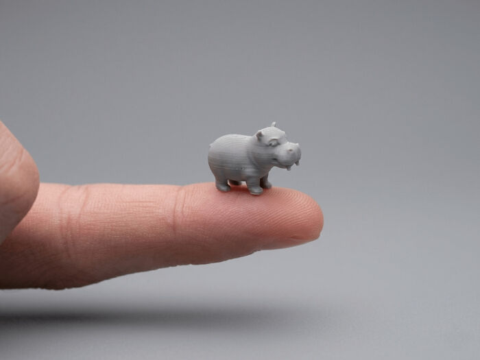 A tiny, useful 3D printed hippo sits on a fingertip, showcasing cool things made with 3D printers.