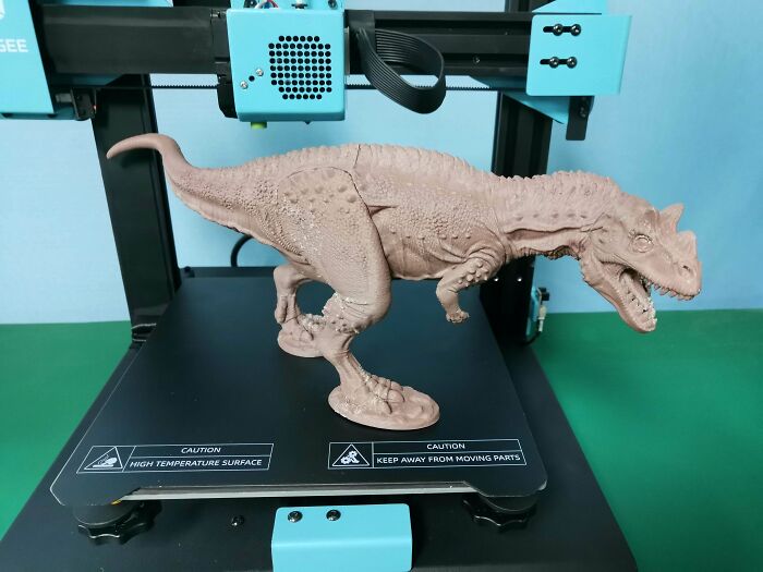 A large, cool 3D printed dinosaur figure stands on a 3D printer, a useful creation by 3D printers.