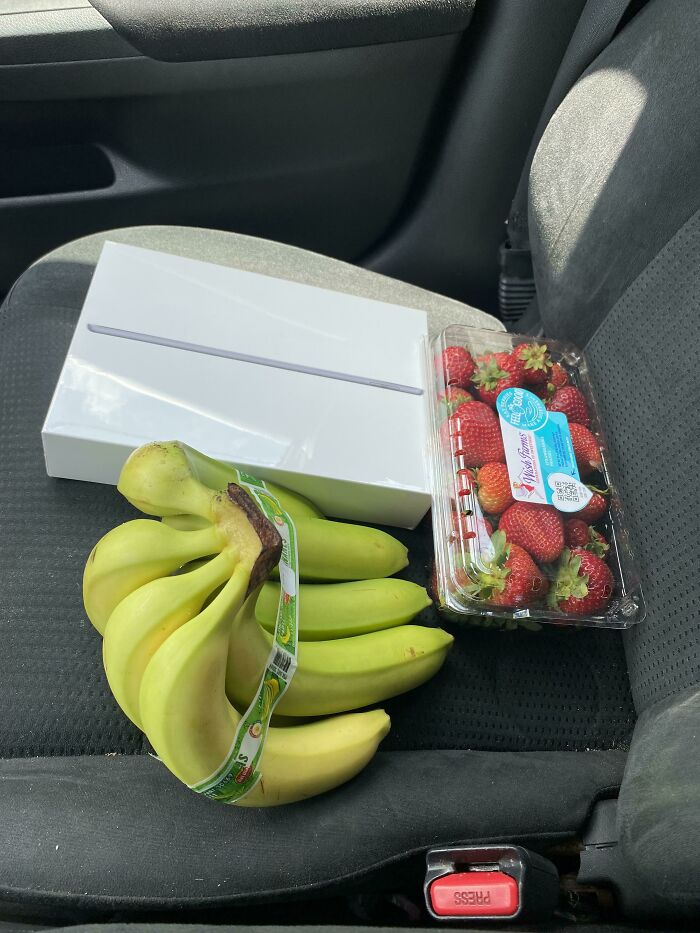 Service industry worker with groceries and an iPad box in a car, highlighting worker dilemmas.