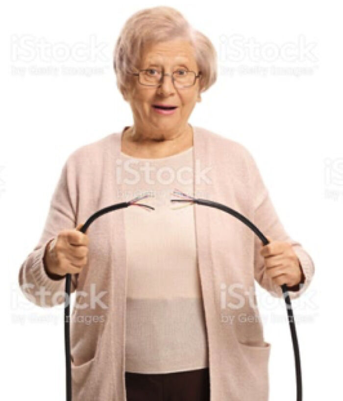 An elderly woman in glasses holding a deliberately cut cable, embodying an act of stupidity or confusion.