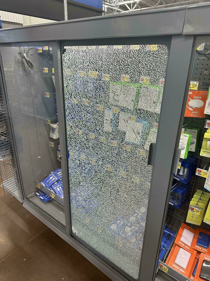 Service industry workers questioning job: a shattered glass door on a display case, revealing products inside.