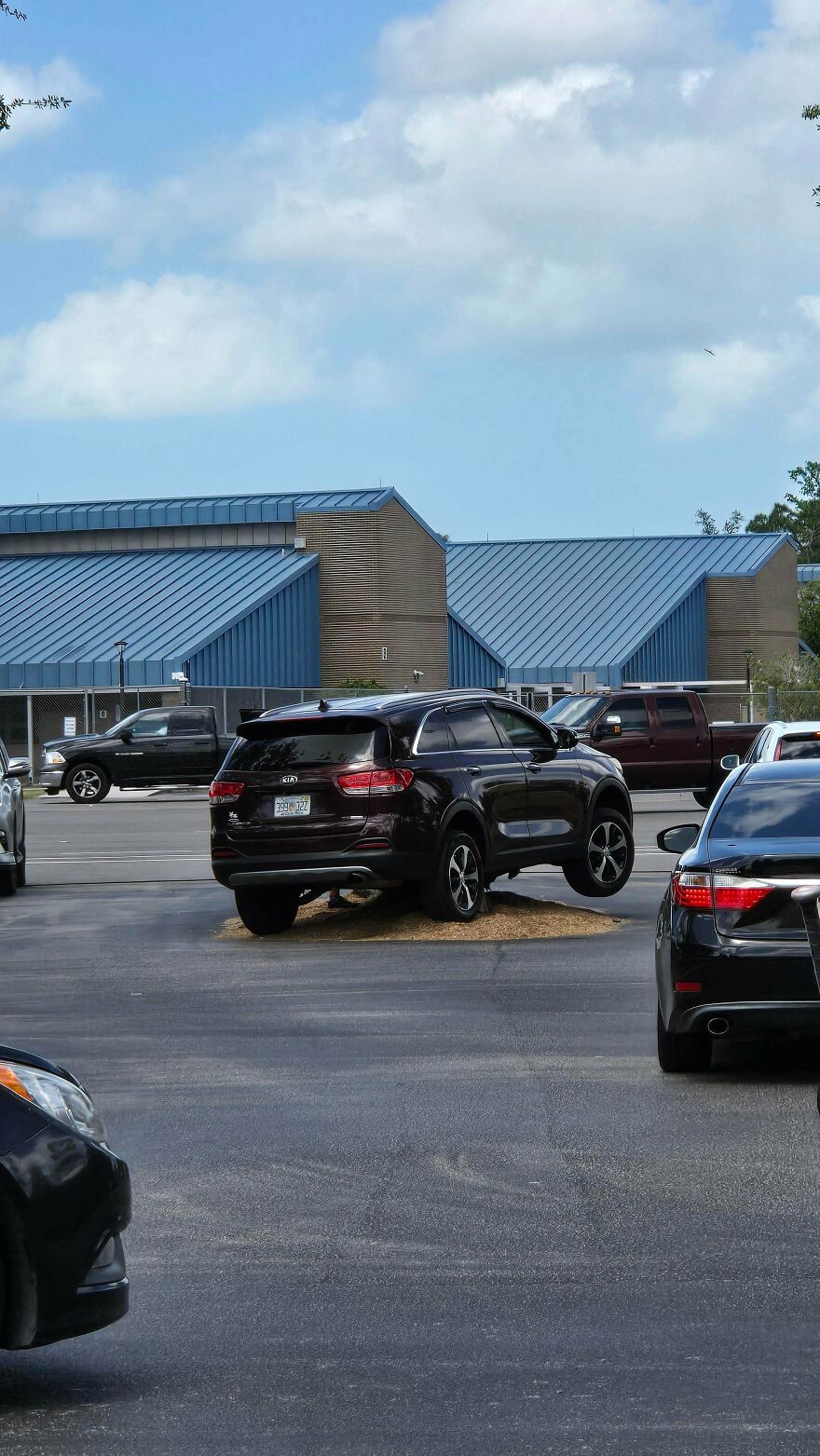 A brown SUV with its front wheels lifted in a parking lot, suggesting a rough day behind the wheel.