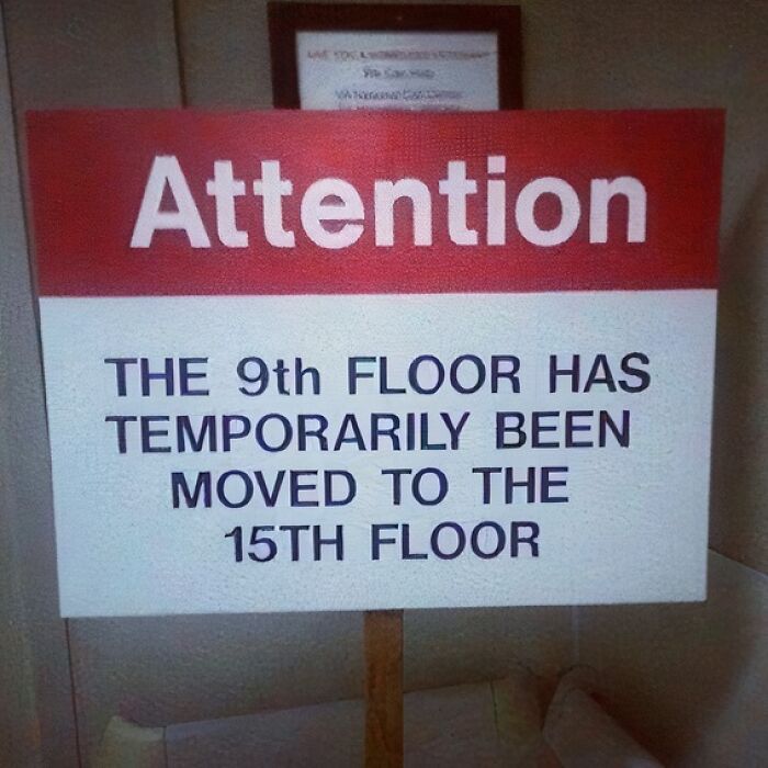 A red and white sign displaying a confusing message that the 9th floor has temporarily moved to the 15th floor, an unfortunate display of stupidity.