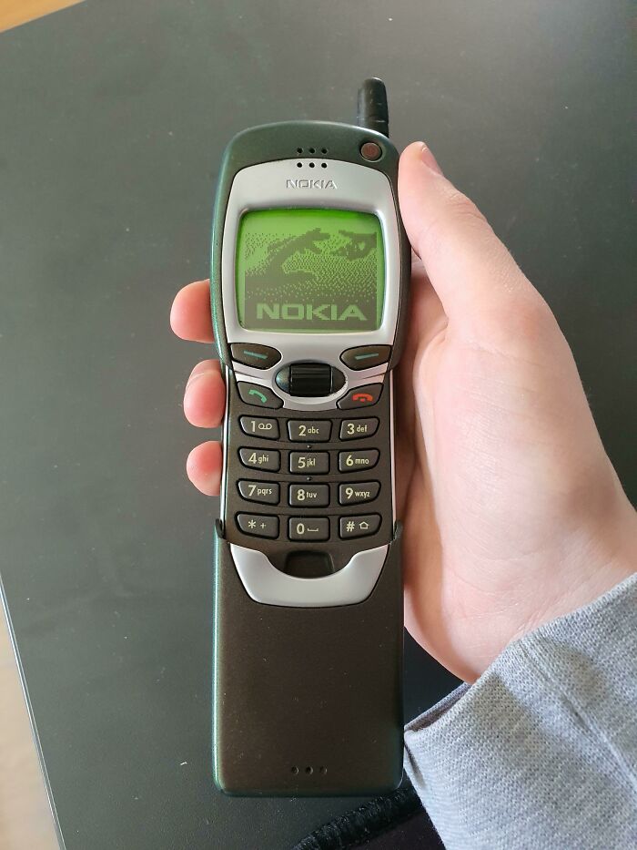 Satisfying and genius technologies: A hand holding a vintage Nokia phone with a bright green screen display.