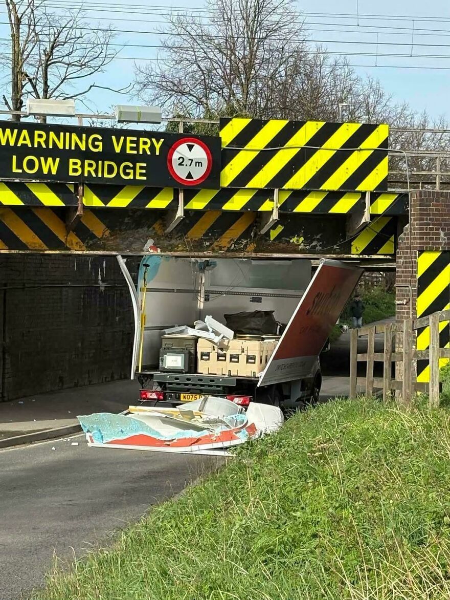A truck with its top torn off after hitting a low bridge, showing a rough day behind the wheel.