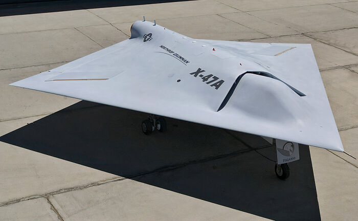 A sleek, grey Northrop Grumman X-47A unmanned combat air vehicle on an airfield, illustrating genius technologies.