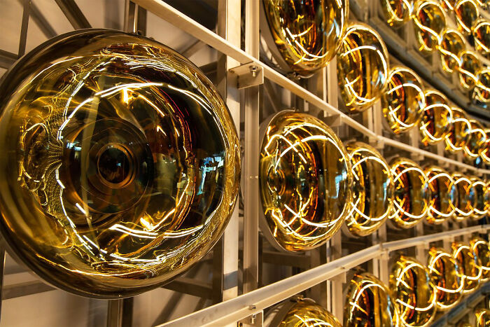 A vibrant display of golden, spherical light fixtures reflecting intricate patterns, symbolizing satisfying and genius technologies.