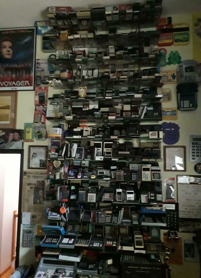 A vast collection of vintage and modern calculators meticulously arranged on a wall, showcasing satisfying technologies that make life easier.