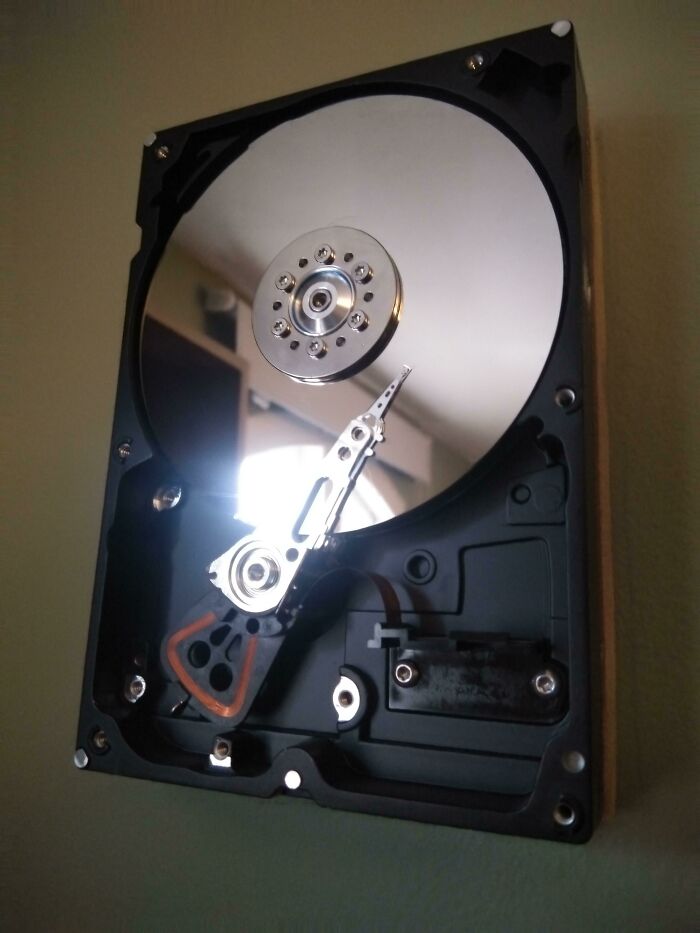 An open hard drive with its reflective platter and read/write head, representing the everyday life technologies.
