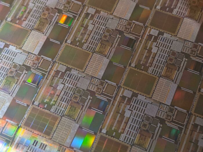 A detailed view of a microchip wafer, highlighting the intricate genius technologies used in modern devices.