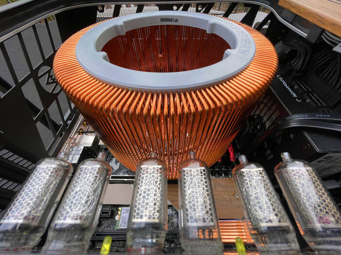 An interior view of a computer showcasing ingenious technologies with a large copper heatsink and glowing vacuum tubes.