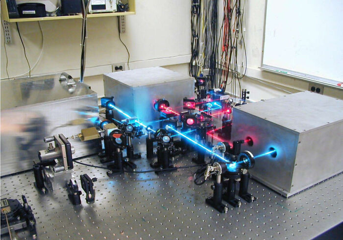 A complex optical setup with red and blue laser beams crossing, showcasing advanced genius technologies.