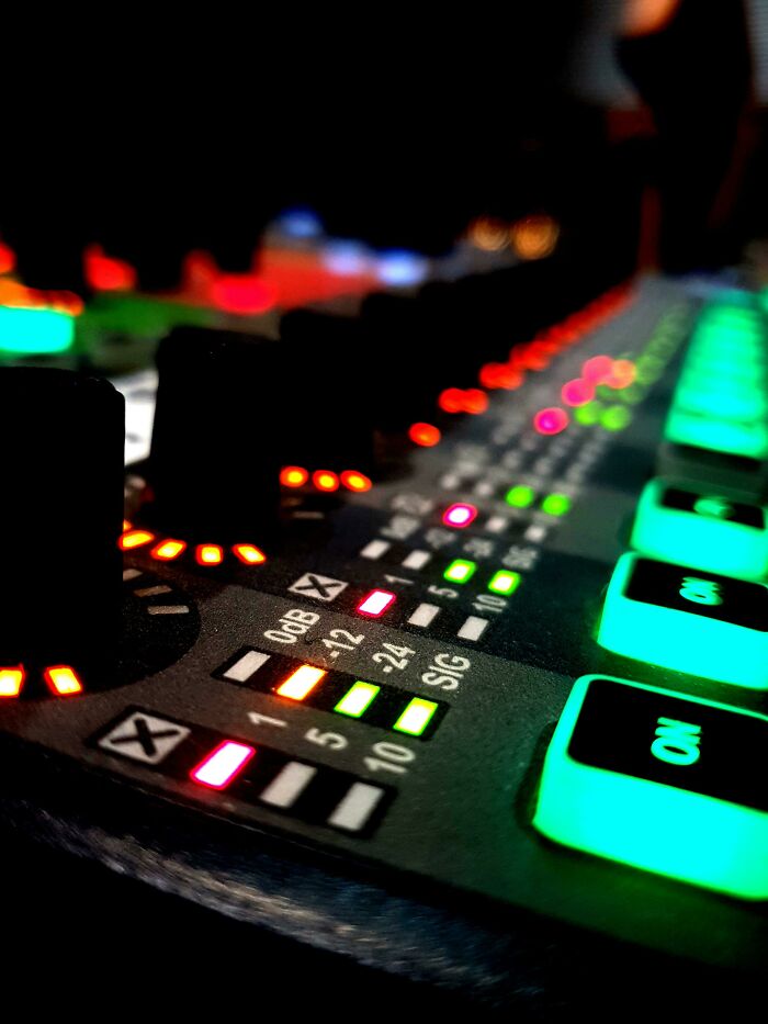 Close-up of an illuminated sound mixing board, highlighting genius technologies in audio engineering.