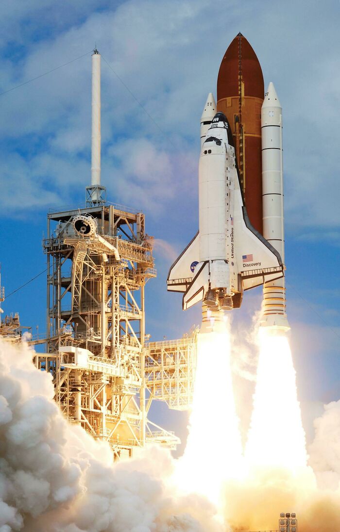 The Space Shuttle Discovery launching with a massive plume of smoke, showcasing genius technologies in action.