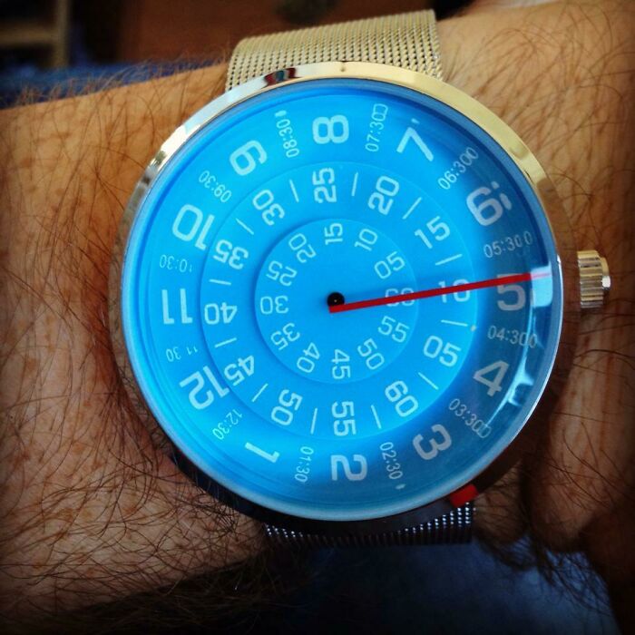 Satisfying and genius technologies: A person wearing a unique blue watch with rotating numbers for time.