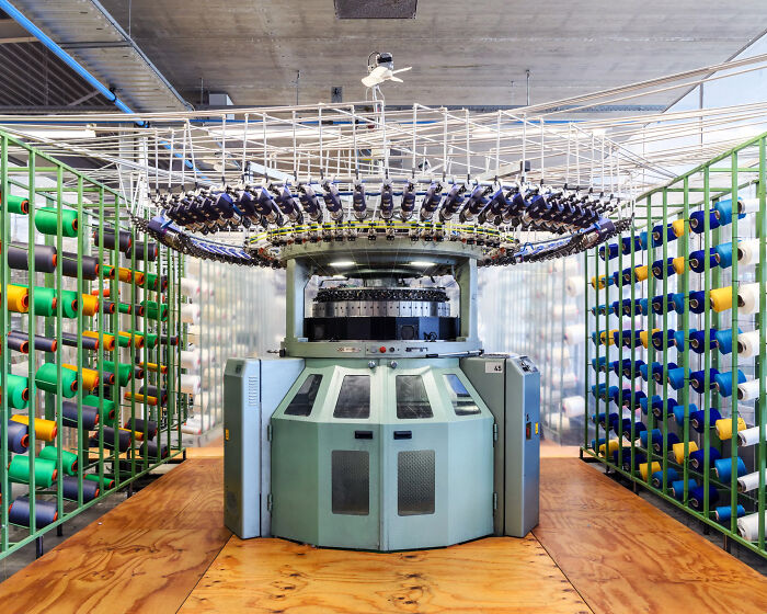 A large industrial knitting machine with colorful spools of thread, showcasing technologies that make everyday life easier.