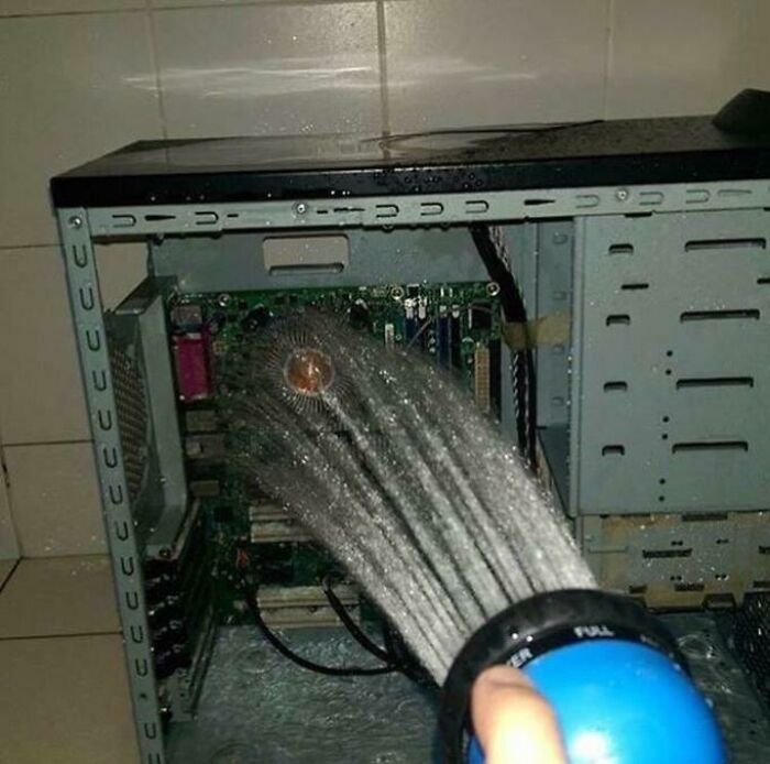 A person hosing down the inside of an open computer tower with water, a truly creepy and confusing image that needs a priest.