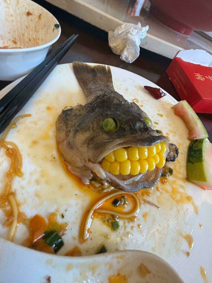 A creepy and confusing image of a fish head with corn kernels for teeth, needing a priest.