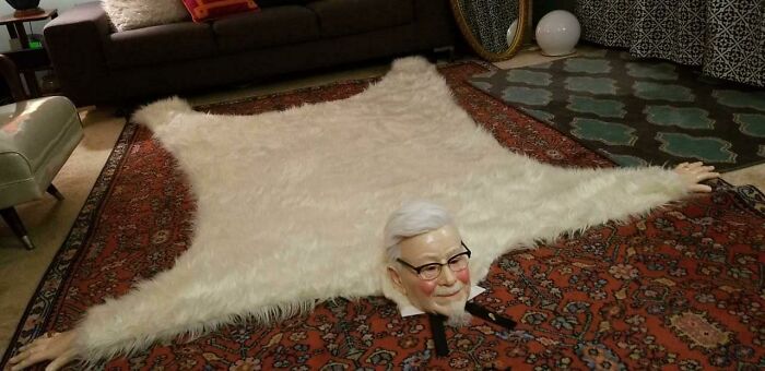 A creepy and confusing image of a white fur rug with the head and arms of Colonel Sanders, needing a priest.