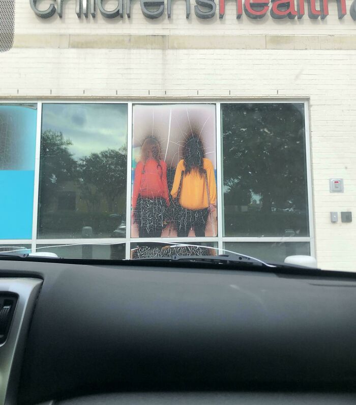 A creepy and confusing image of two figures resembling children behind a cracked window, needing a priest.